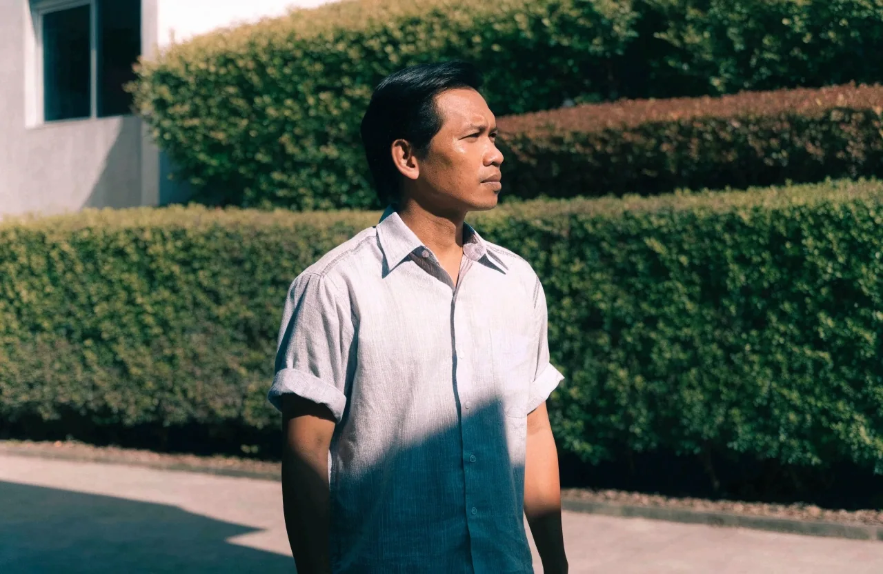 Man standing in a sunlit courtyard with morning light across his arm